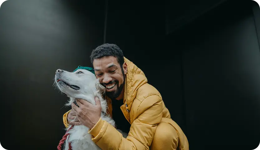 Man joyfully hugging a dog, symbolizing the bond and support in mental health care at Willow.