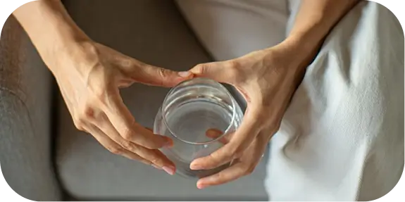 Hands resting on lap holding a glass, symbolizing calmness during mental health intake assessment at Madison clinic.