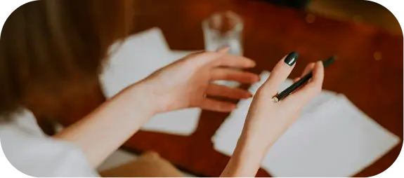 Person gesturing with a pen over paperwork during personalized treatment planning.