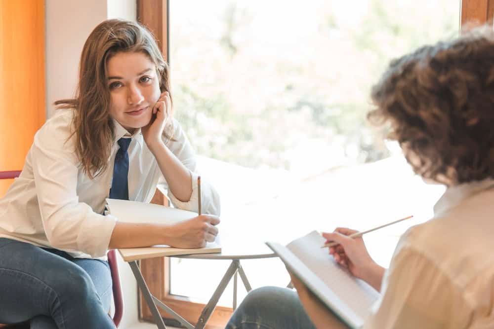 Teenager doing homework near friend