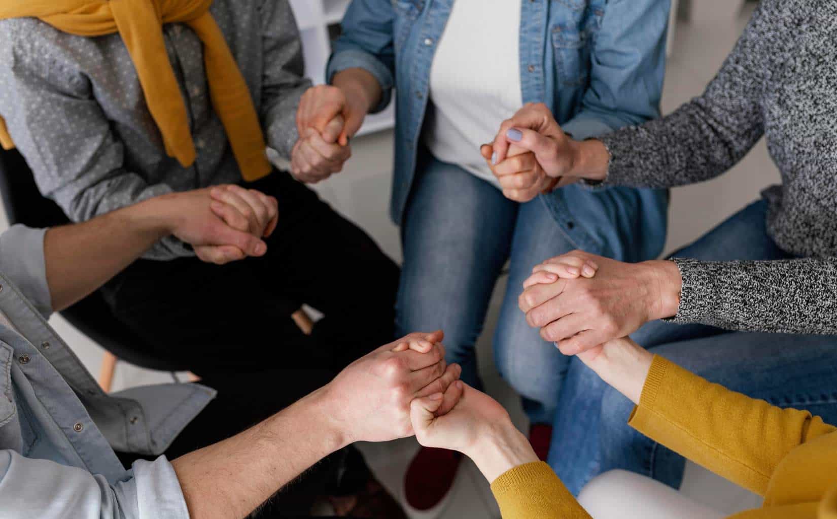 Support group holding hands during cocaine addiction treatment in Madison, WI.