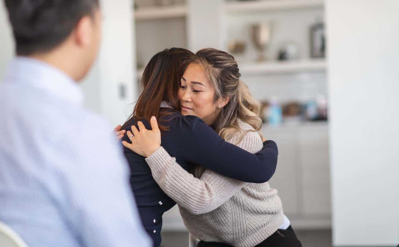 Woman sharing a supportive hug during heroin addiction treatment in Madison, WI.